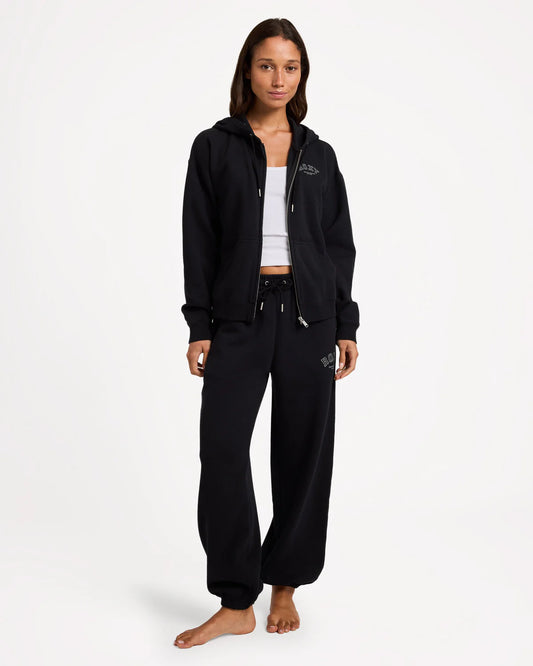 Person wearing a black hoodie and pants with a logo on a white background