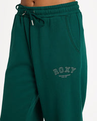 Green sweatpants with 'ROXY' branding on a white background