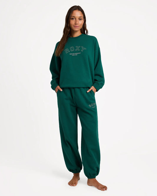Person wearing a green Roxy sweatshirt and pants on a white background