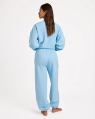 Person wearing a light blue sweatshirt and pants on a white background
