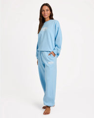 Woman wearing a light blue pajama set with a logo on a white background
