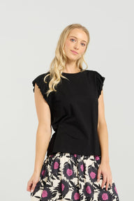 Woman wearing a black top and floral skirt on a white background