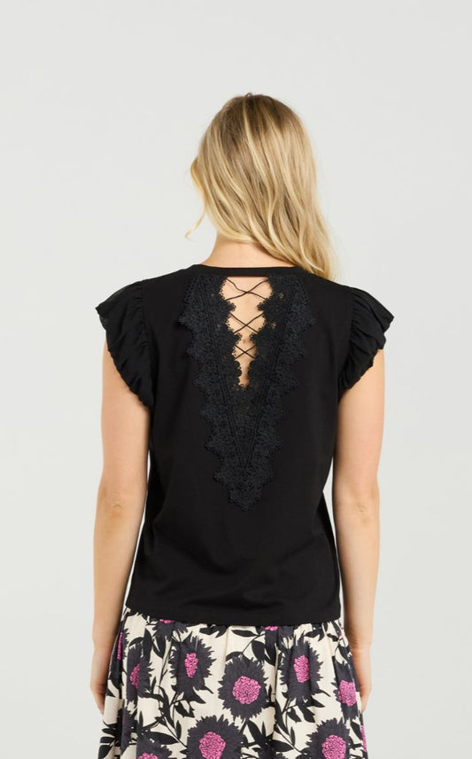 Woman wearing a black top with lace-up back and a floral skirt on a white background
