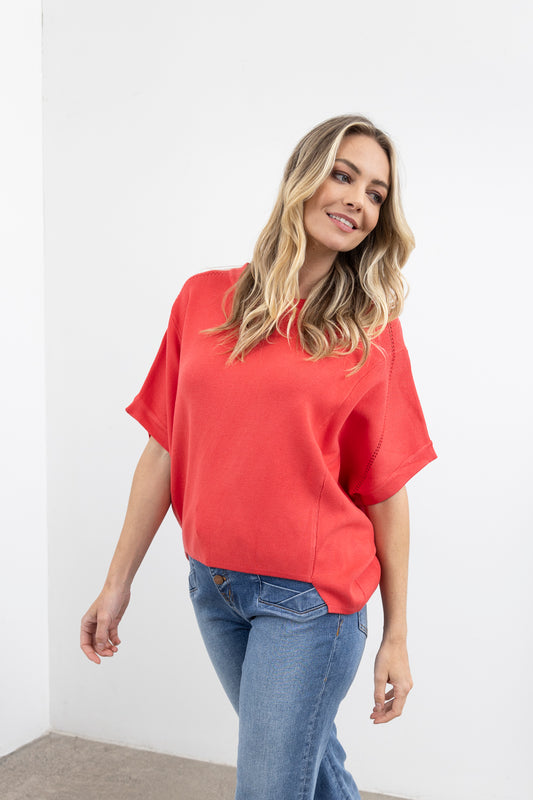 Woman wearing a pink top and blue jeans against a white background