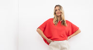 Woman wearing a pink knit and blue jeans on a white background
