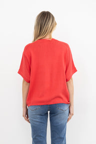 Woman wearing a pink knit and blue jeans on a white background