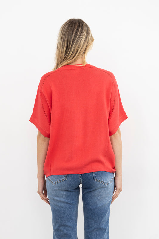 Woman wearing a pink knit and blue jeans on a white background
