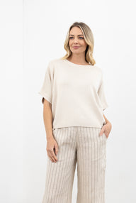 Woman wearing a beige top and striped pants on a white background