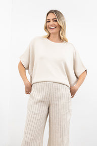 Woman wearing a beige sweater and pants on a white background