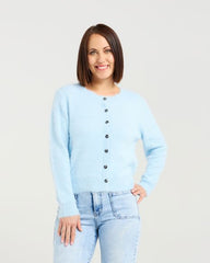 Woman wearing a light blue cardigan and jeans on a white background