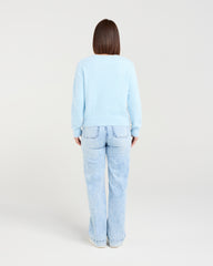 Person wearing a light blue sweater and jeans on a white background