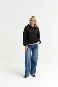 Woman wearing a black hoodie and blue jeans on a white background