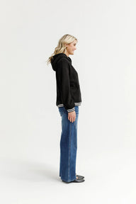 Woman wearing a black hoodie and blue jeans on a white background