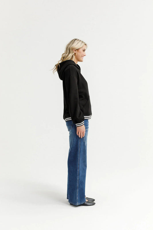 Woman wearing a black hoodie and blue jeans on a white background