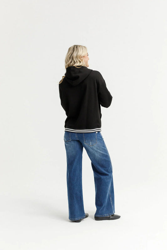 Person wearing a black hoodie and blue jeans on a white background