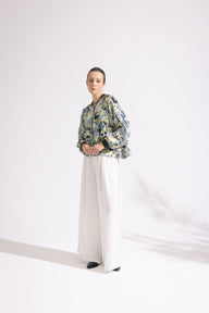 Person wearing a floral jacket and white pants on a white background