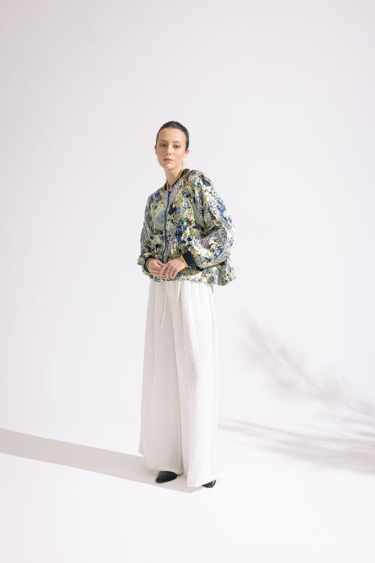Person wearing a floral jacket and white pants on a white background