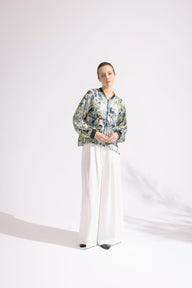 Person wearing a floral jacket and white pants on a white background