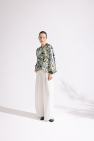 Person wearing a floral jacket and white pants on a white background
