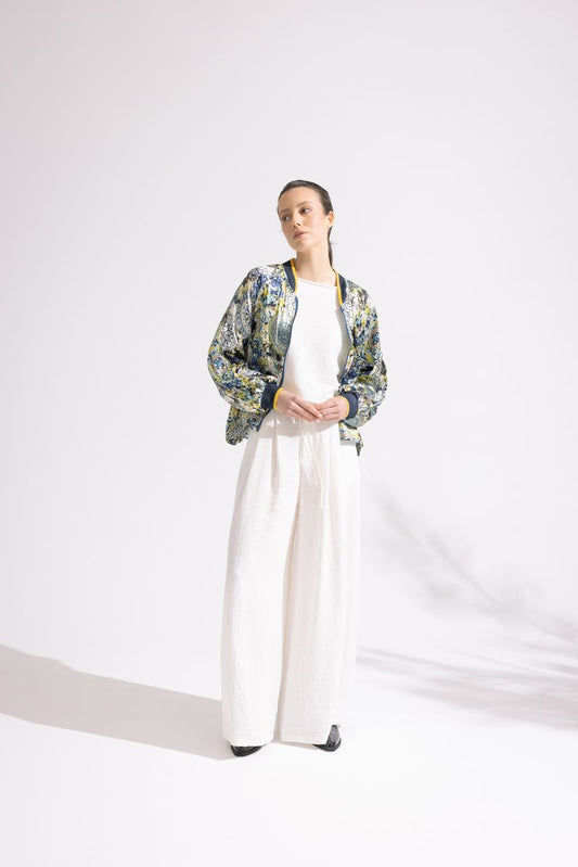 Person wearing a floral jacket and white pants on a white background
