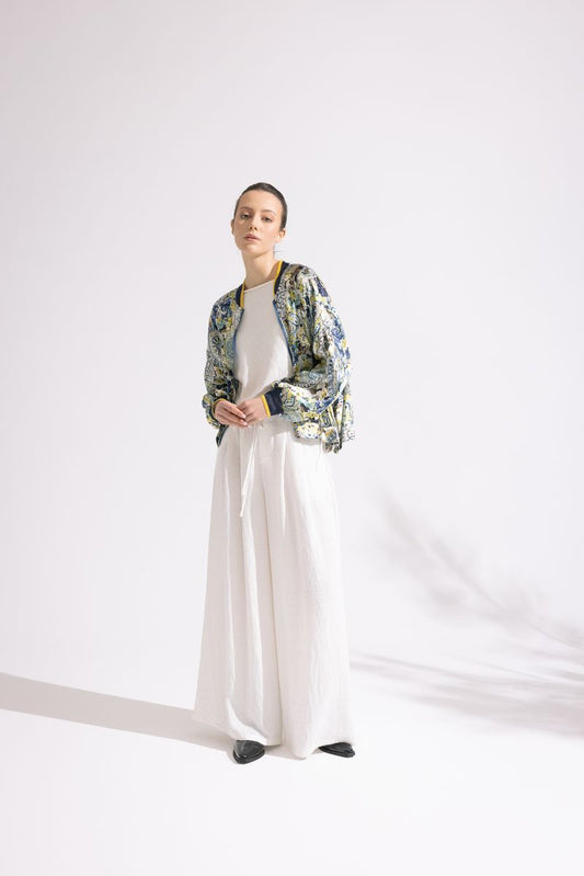 Person wearing a floral jacket, white shirt, and white pants on a white background