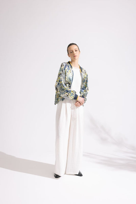 Person wearing a floral jacket, white top, and white pants on a white background
