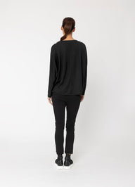 Person wearing a black long-sleeve top and black pants on a white background