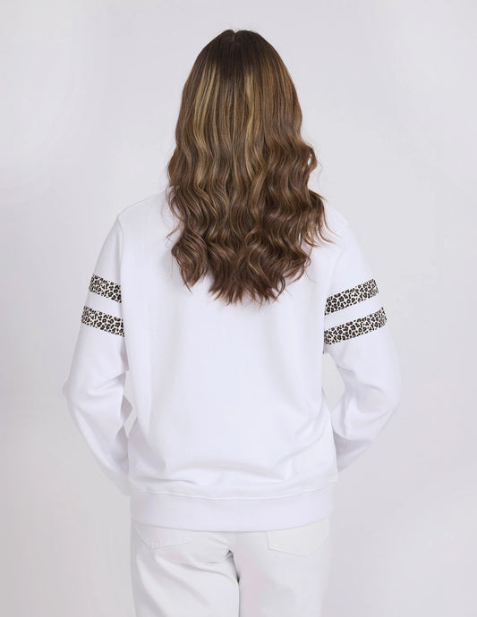 Person wearing a white sweatshirt with leopard print sleeves on a plain background