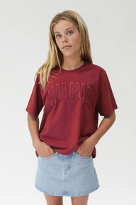 Woman wearing a red t-shirt with text and a denim skirt on a white background