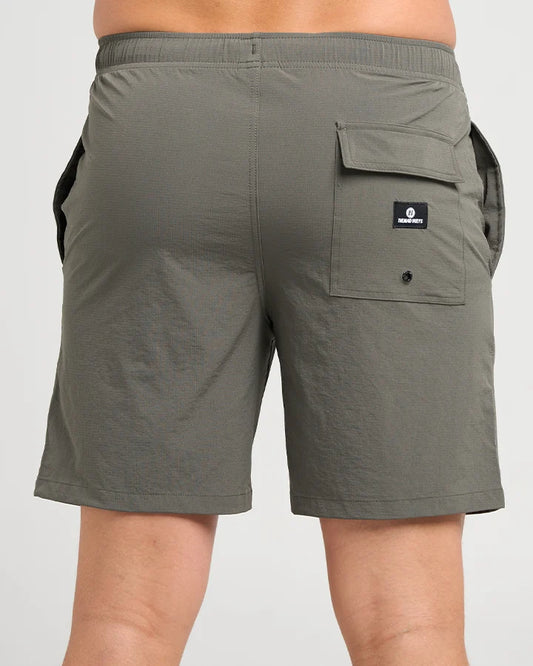 A close-up back view of a person wearing olive green cargo shorts with a side pocket and a black brand patch reading 'WILDERNESS' on the back pocket.