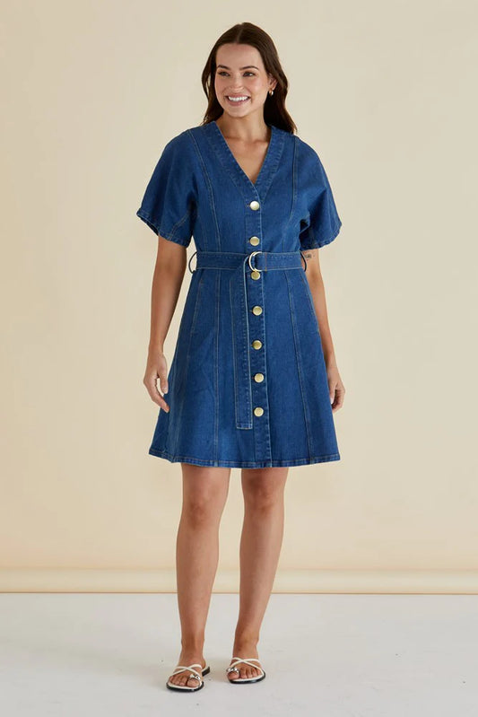 Woman wearing a blue denim dress with a belt against a beige background