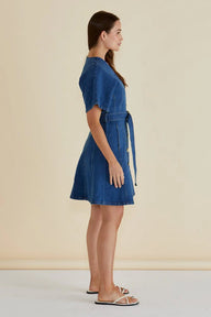 Woman wearing a blue denim dress against a beige background