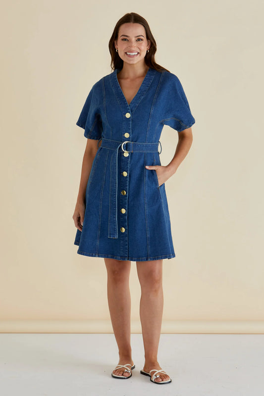 Woman wearing a blue denim dress with a beige background