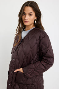 Woman wearing a quilted brown jacket on a white background