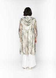 Person wearing a long, patterned dress with a hood against a white background