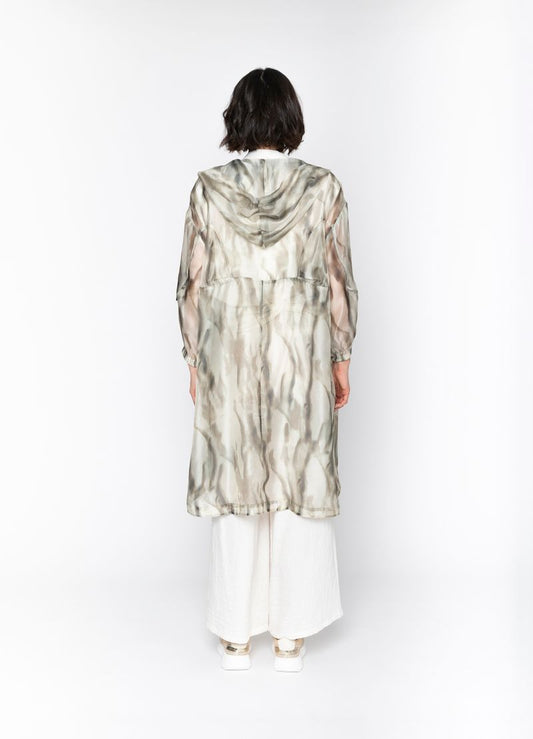 Person wearing a long, patterned dress with a hood against a white background