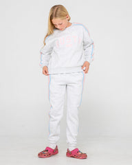 Young girl wearing a white tracksuit with colorful accents on a plain background