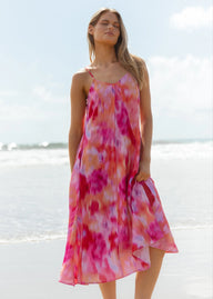 Woman wearing a pink floral dress on a beach