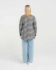 Person wearing a patterned shirt and light blue jeans on a white background