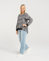 Woman wearing a patterned sweater and light blue jeans on a white background