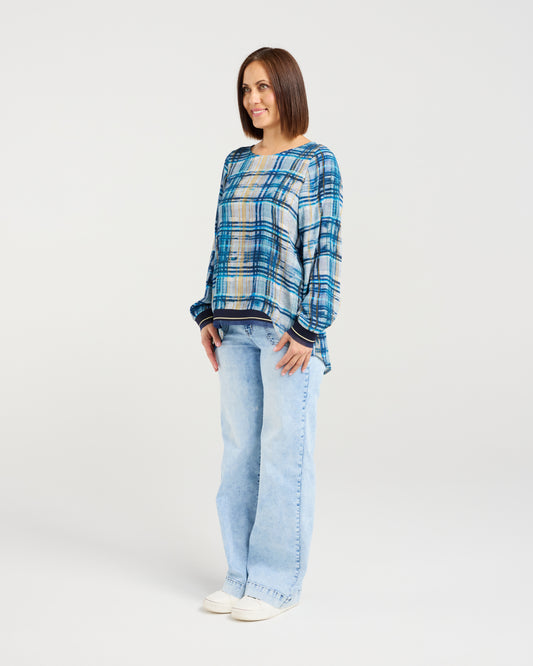 Woman wearing a blue plaid shirt and light blue jeans on a white background