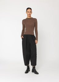 Woman wearing a brown sweater and black pants on a white background