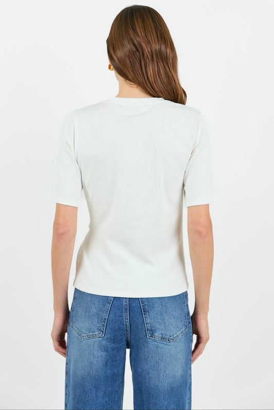 A woman viewed from the back wearing a plain white short-sleeve t-shirt and blue jeans against a light gray studio background.