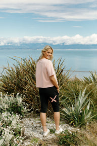 Lady wearing Home-Lee 3/4 Apartment Pants in Black with Blossom Berry X on  standing on a path with scenic ocean background