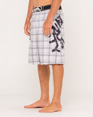 Person wearing plaid shorts with a logo on a white background