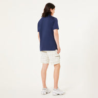 Person wearing a navy blue shirt and white shorts on a light gray background
