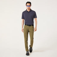 Man wearing a Navy blue polo shirt & green pants on a light gray background