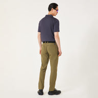 Man wearing a Navy blue polo shirt & green pants on a light gray background