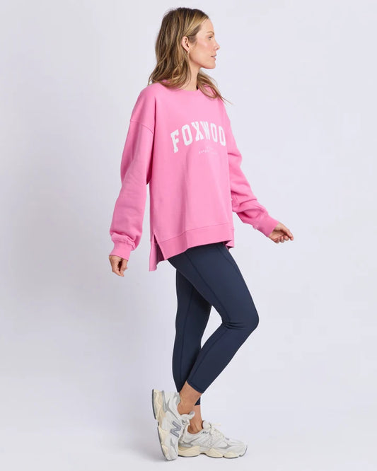 Person wearing a pink 'FOXWOOD' sweatshirt and navy leggings on a white background
