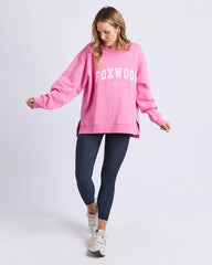 Person wearing a pink 'FOXWOOD' sweatshirt and navy leggings on a white background